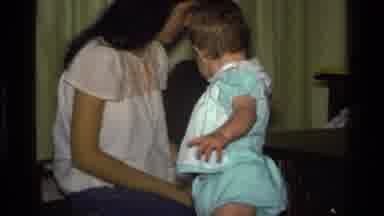 CALIFORNIA USA-1977: Mother and Baby Play with Red Ribbon in Home