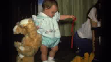 California USA (1977): Smiling Woman And Man Watch Baby Drop And Pick Up Teddy