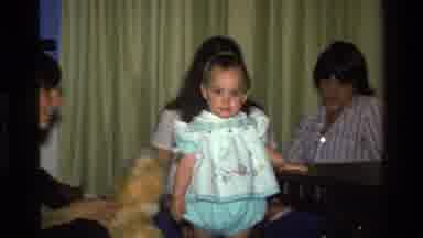 California USA (1977): Female Baby With Dress Walking With Adults In The