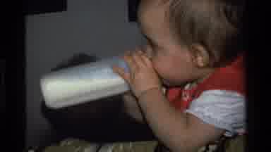 California USA (1977): A Baby On A Crib Drinking Milk From His Bottle