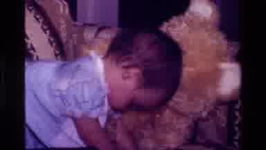 California USA (1977): Baby In Blue Dress Snuggling With Bear And Playing With