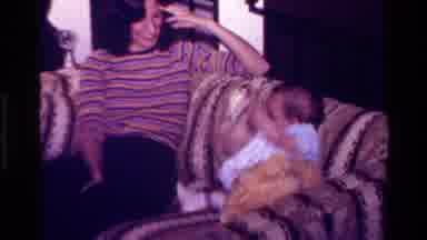 California USA (1977): Infant Child Clad In A White Dress Playfully Wags Her Arms