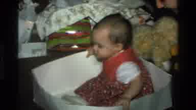 California USA (1977): A European Baby Is Playing In On Box On Christmas Morning