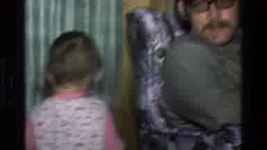 California USA (1977): Baby Girl Walking Behind Adult In Chair In The 70'S