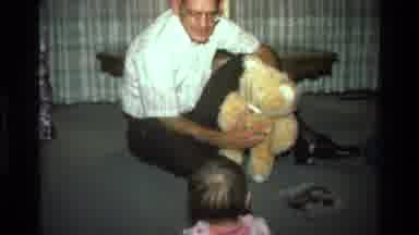 California USA (1977): A Middle-Aged Man And A Baby Play With A Plush Animal In