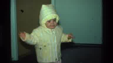 California USA (1977): Cute Baby In Yellow Jacket Waddles To Get Book From Parent