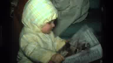 California USA (1977): Baby In Yellow Coat Picking A Newspaper Up And Trying To