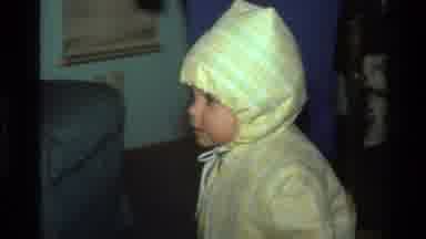 California USA (1977): Happy Kid Smiling Wearing Yellow Rain Coat In House