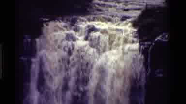 KENYA-1983: A Very Full Waterfall Flowing Over Rocks With Rocks On The Side