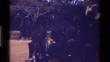 Kenya (1983): Dark-Skinned Tribesmen Stand In A Group Bouncing Up And Down Wearing