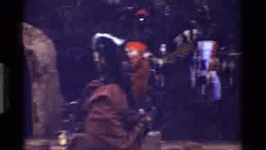 Kenya (1983): People Wrapped In Brown Robes Standing Near Brown Grass Huts