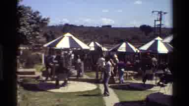 Mara Tanzania (1983): People Hanging Out Outside Under Several Gazebos