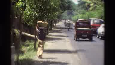 Singapore (1984): Vehicular Traffic Uses A Busy Street Lined With Trees Followed