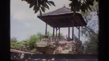 Singapore (1984): Two Adults Approach An Old Traditional Structure Amid Palms And