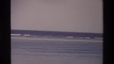 Singapore (1984): People Playing In Waves At The Beach And A Sailboat With