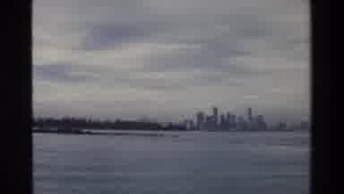 Singapore (1984): Zoom In On A City Skyline Across A Large Body Of Water With Low