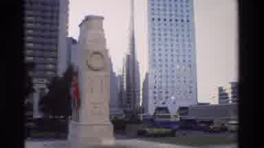 Hong Kong (1984): A Green Bus Drives Through City Statue In Front Of Skyscrapers