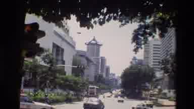 Thailand (1984): Man Walking Near Street With Cars Driving By With Buildings In
