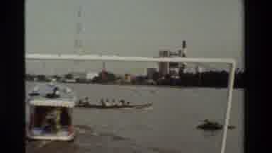 Thailand (1984): A Group Of People Are Riding A Motorized Longboat Through A Busy