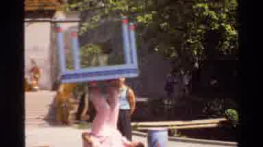 Thailand (1984): A Person Balancing Out A Table In Front Of Other People In The