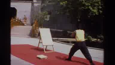 Thailand (1984): A Man Throwing Metal Stick Against A Board In An Asian Country