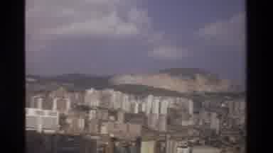 Thailand (1984): A Beach And A Large City With Mountains Filmed From A Plane