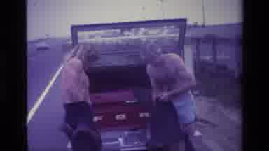 Laguna Beach California USA (1977): Two Men Getting Dressed Behind Red Truck On A