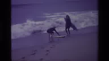 Laguna Beach California USA (1977): Two People On A Beach Attempting To Surf The
