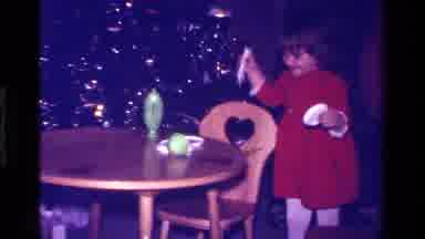 California USA (1979): A Young Girl In A Red Dress Is Opening Up A Bottle In Front