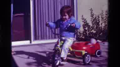 California USA (1979): Little Girl Riding Tricycle With Wagon In A Circle On Patio