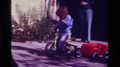 California USA (1979): Little Kid Biking On His Two Wheeler With A Wagon Attached