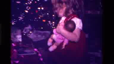 California USA (1979): A Little Girl Holding Her Doll And Unwrapping Her Other