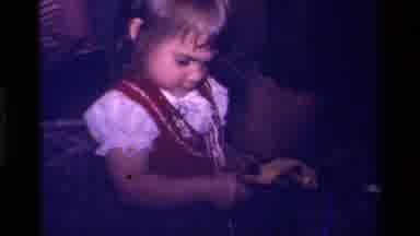 California USA (1979): Young Child Wearing Jumper Opening Gift In Yellow Wrapping