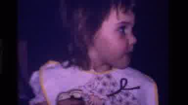 California USA (1979): Little Girl With A White And Yellow Bib On Looking Around