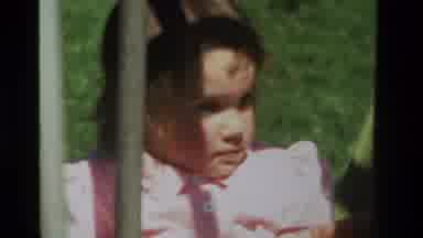 California USA (1979): A Girl Toddler In Pink Attempts To Climbs A Money Bar