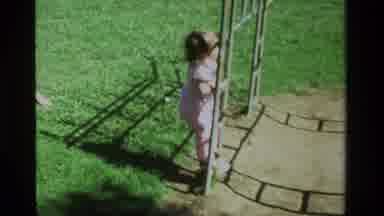 California USA (1979): Little Girl In A Pink Shirt And Shorts Trying To Climb Up A