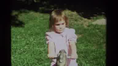 California USA (1979): Little Girl In A Pink Dress Having Fun Sitting On Top Of A