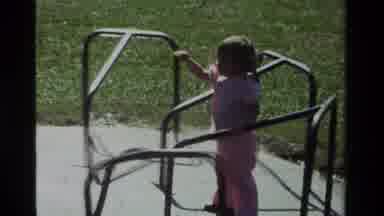 California USA (1979): Toddler Being Spun On Merry Go Round By Adult Play Outdoors