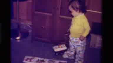 California USA (1979): Small Child Dragging A Toy On The Ground At Home