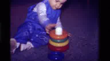California USA (1979): Child Playing Stacking Colored Rings On A Toy Sitting On