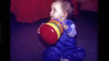 California USA (1979): Young Child Playing On The Floor With A Ring Toy With Four