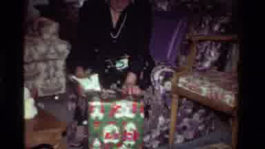 California USA (1981): Two Individuals Opening Christmas Gifts In Two Different