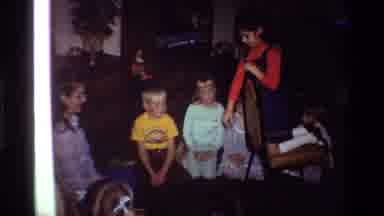 California USA (1981): Girl Dropping Something On The Floor With A Circle Of Young