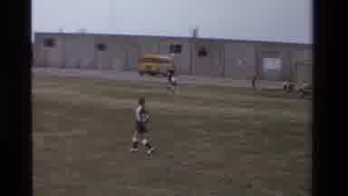 California USA (1981): Young Children Playing On A Soccer Field Outside Of A
