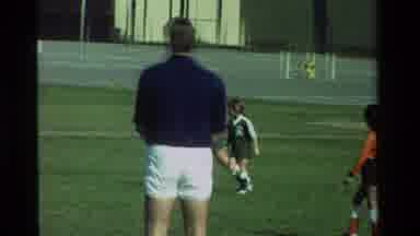 CALIFORNIA USA-1981: Children Playing Soccer On A Grassy Field Near A Street