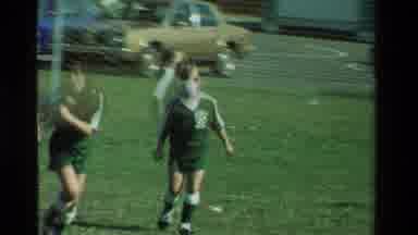 California USA (1981): Children Green And Red Soccer Uniforms Filed Grass Old Cars