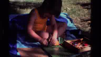 California USA (1981): Small Girl Playing On A Blanket With Toys Outside On A