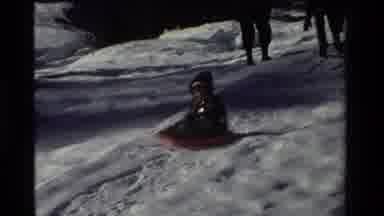 California USA (1981): Little Boy Sliding Down A Hill On A Saucer While The Adults