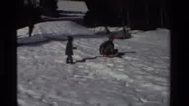 California USA (1981): A Father And His Son Sledding From The Top Of A Snowy Hill