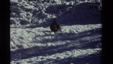California USA (1981): Man In Dark Clothes Sitting And Sliding On Snowy Hill